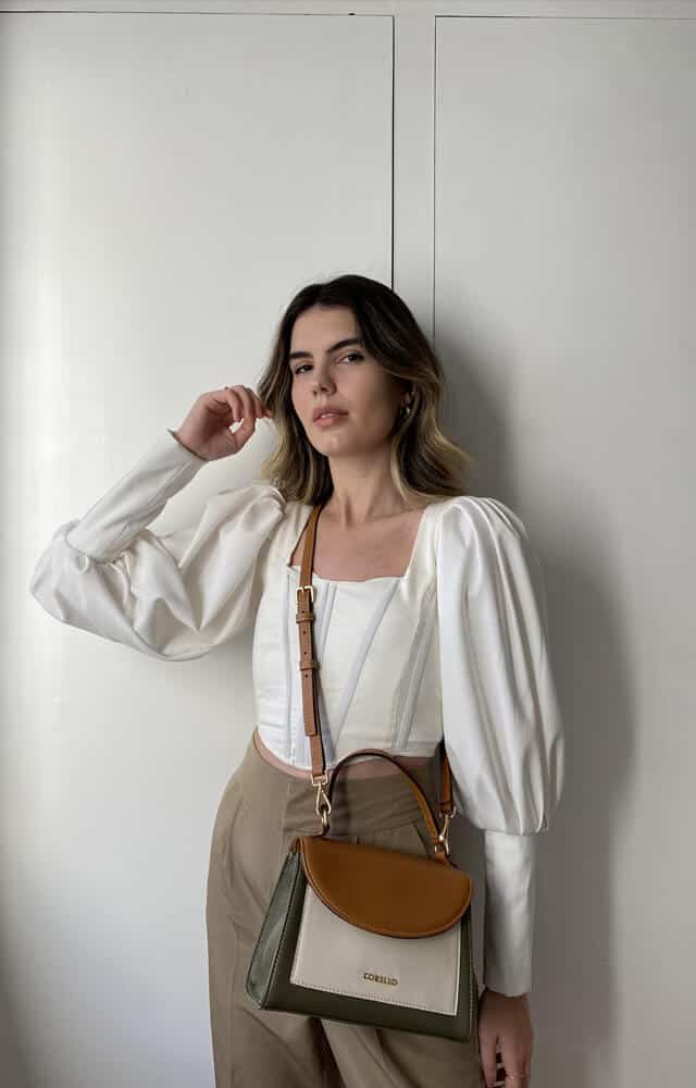 como usar bolsa transversal - modelo com blusa branca, calça cinza e bolsa marrom 