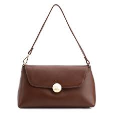 Bolsa de mão feminina Corello em couro liso marrom com formato envelope e fecho geométrico de esfera dourada, acompanhada de alça fina ajustável.